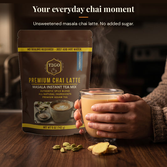 Hands holding a glass mug of unsweetened masala chai latte next to a T2GO pouch