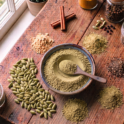 T2GO Extra Cardamom Chai Masala in a bowl surrounded by cardamom pods, cinnamon, cloves, ginger and pepper