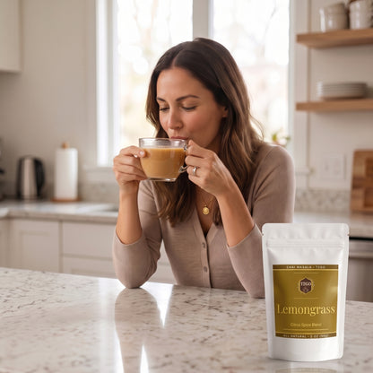 Woman sipping lemongrass masala chai in a bright kitchen next to a T2GO Lemongrass Chai Masala pouch