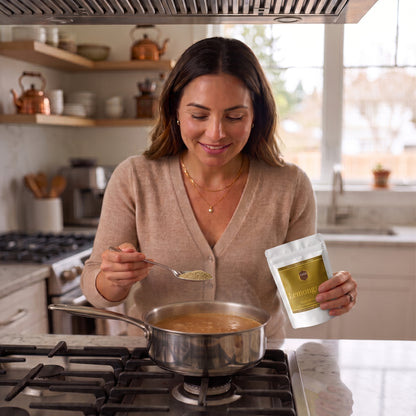 Spooning T2GO Lemongrass Chai Masala into a pot of simmering chai on the stovetop