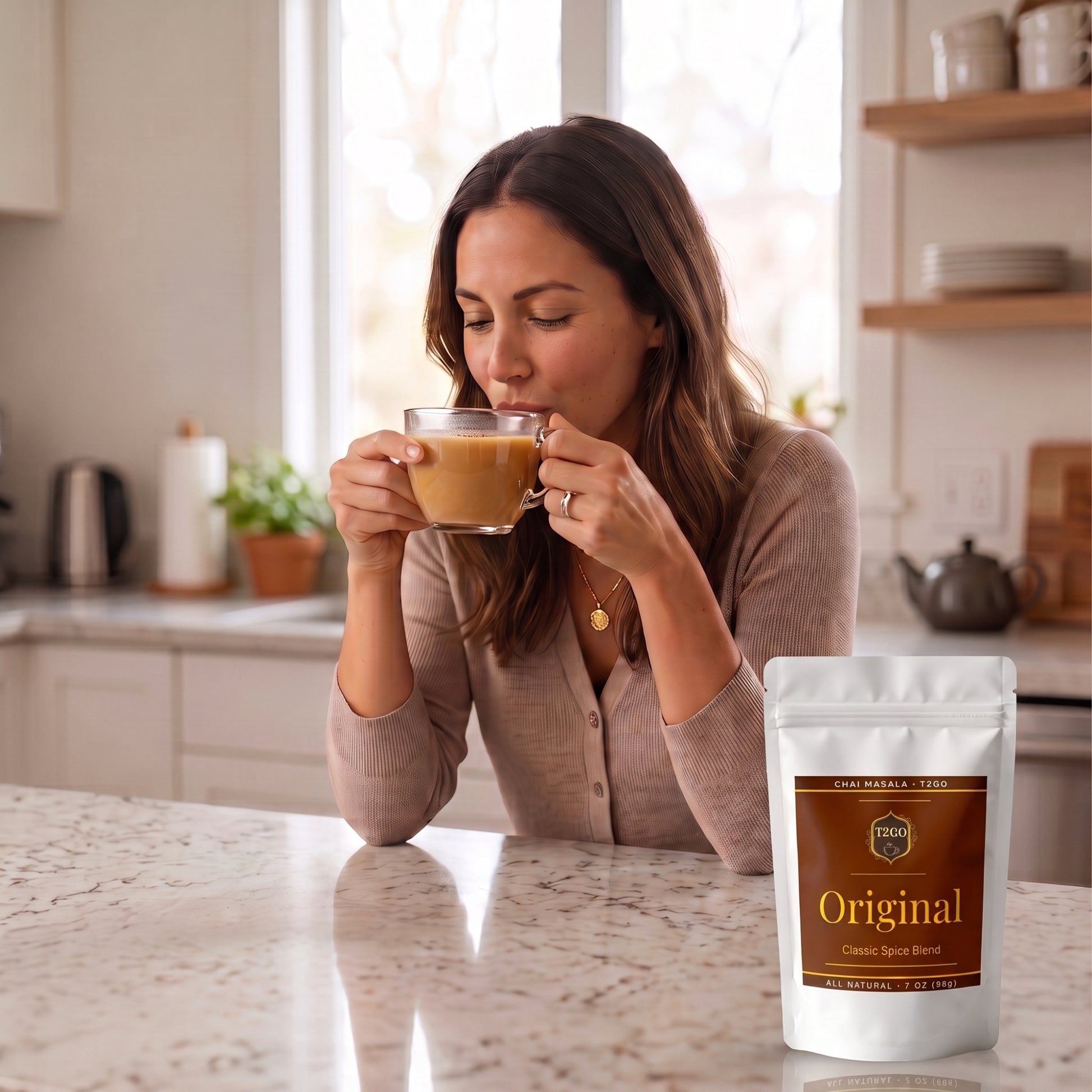 Woman sipping classic masala chai in a bright kitchen next to a T2GO Original Chai Masala pouch