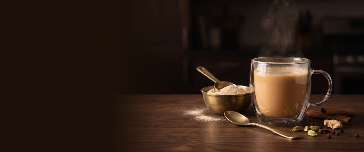 Instant chai latte in a glass mug with chai powder in a brass bowl, cardamom and ginger