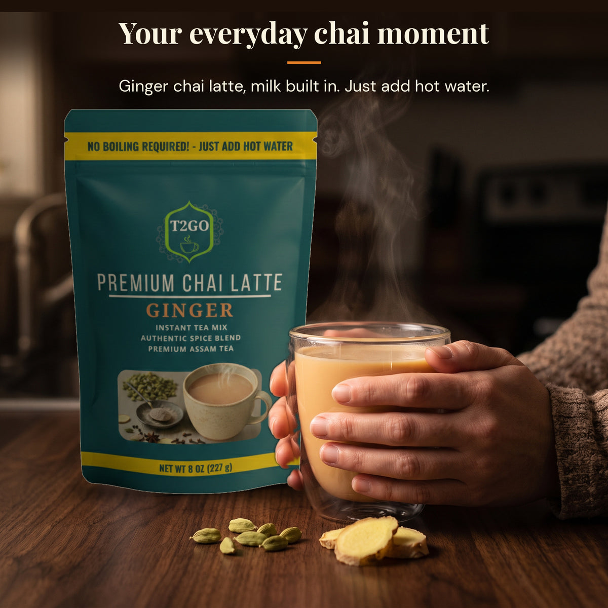 Hands holding a glass mug of hot ginger chai latte next to a T2GO Ginger instant chai pouch