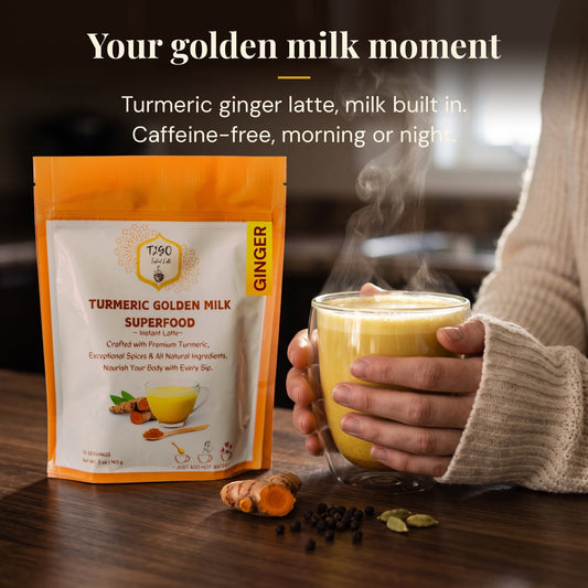 Hands holding a glass mug of turmeric ginger golden milk latte next to a T2GO pouch
